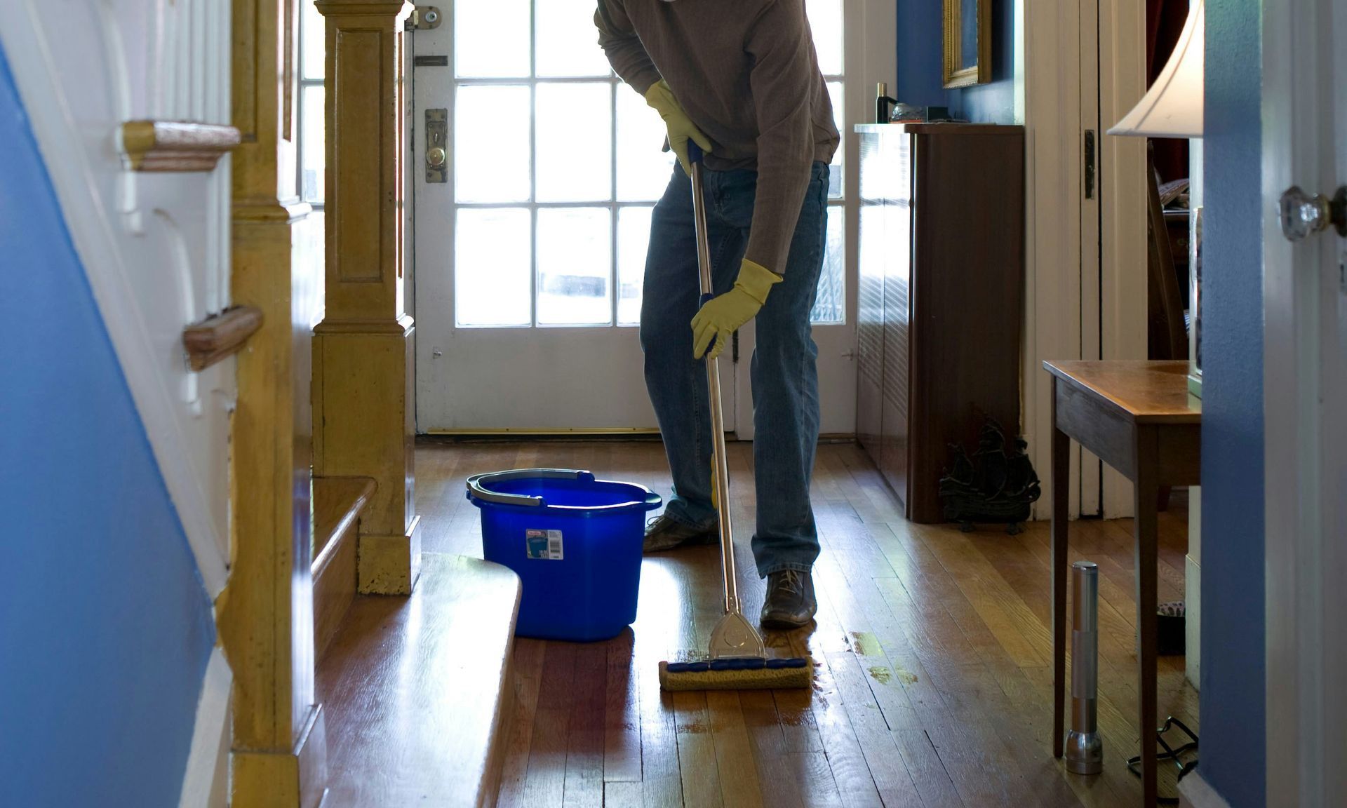 man in gray hoodie and blue denim jeans standing on brown wooden parquet flooring